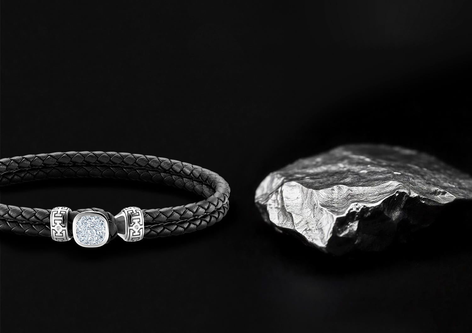MAGIOR Lederarmband mit kristallinem Osmium-Besatz neben einem rohen Osmium-Stück